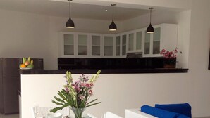 A dining area with a white table set for six, surrounded by white wicker chairs. - Villa Sari Agung (Tibubeneng)