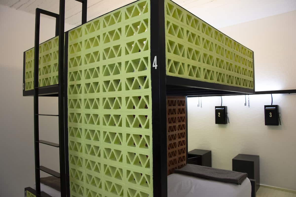A bunk bed with a geometric patterned partition, numbered room 4, and a small desk with a speaker.