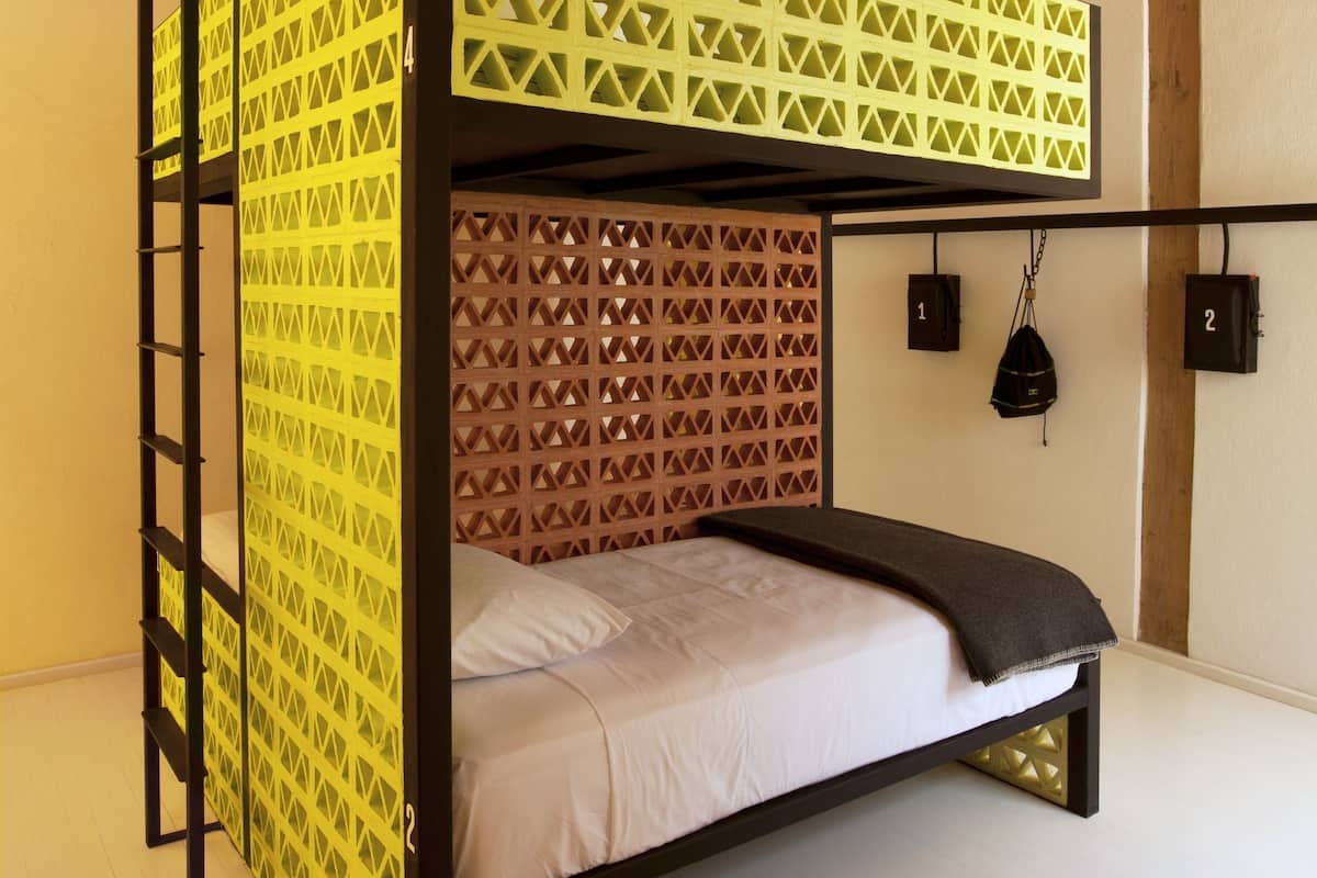 A bunk bed with a geometric patterned headboard, a ladder, and a headboard with a diamond pattern. There are two hooks on the wall.