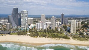 A coastal cityscape with high-rise buildings, a beach, and ocean waves.