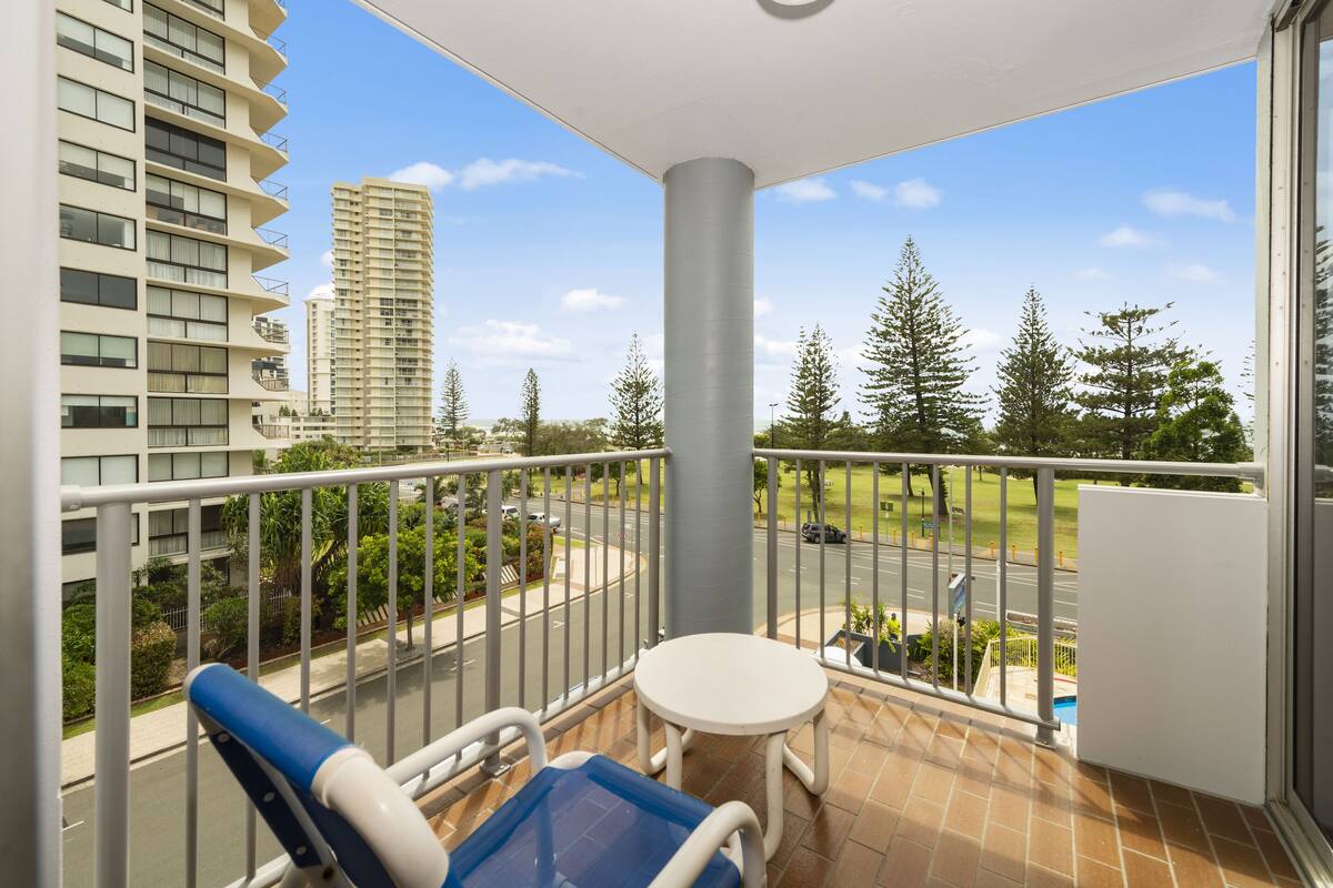 A balcony with a view of a road, trees, and high-rise buildings.
