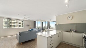 A modern kitchen with a central island, a dining area with a sofa, and large windows offering a view.