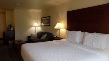 Una habitación de hotel con una cama grande, dos mesitas de noche, un escritorio, una silla y dos lámparas.