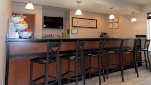 Zona de bar con mostrador, varios taburetes y una exhibición de frutas.
