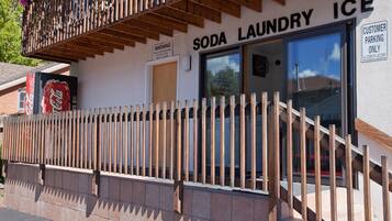 Eine Schaufensterfront mit Holzzaun, einem Coca-Cola-Schild und einem Schild mit der Aufschrift 'SODA LAUNDRY ICE' sowie Kundenzufahrtsmöglichkeiten.