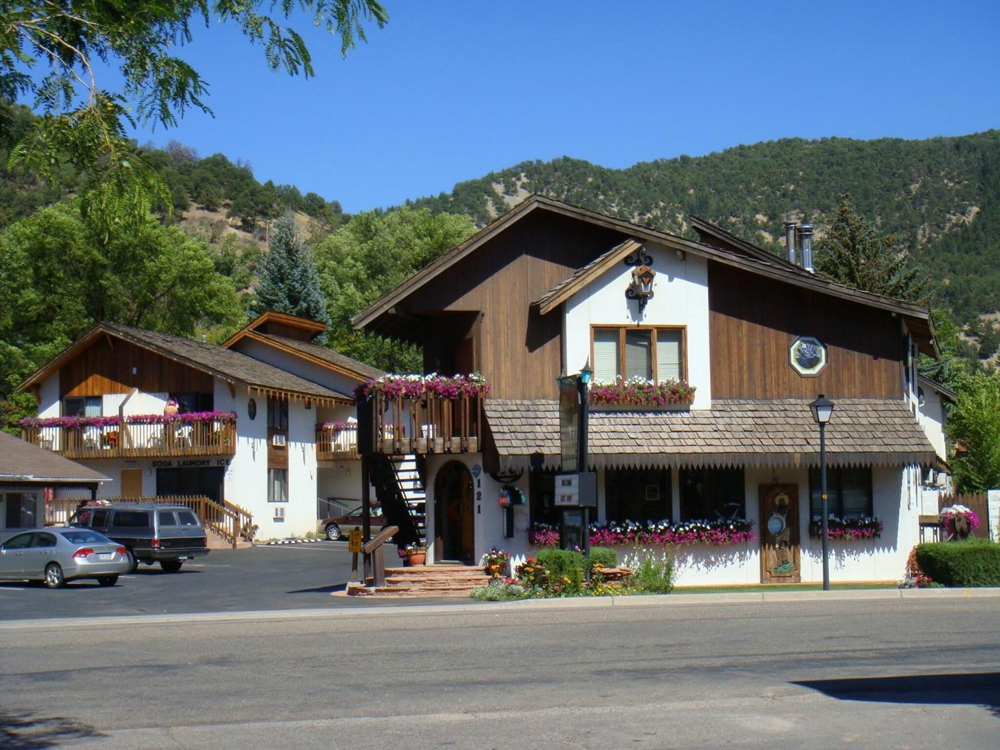 A traditional wooden building with a balcony and flower boxes, located in a mountainous area.