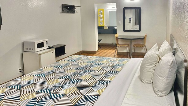 A hotel room with a bed, a desk, a chair, a microwave, and a mirror. - Motel 6 Huntington, WV (Huntington)