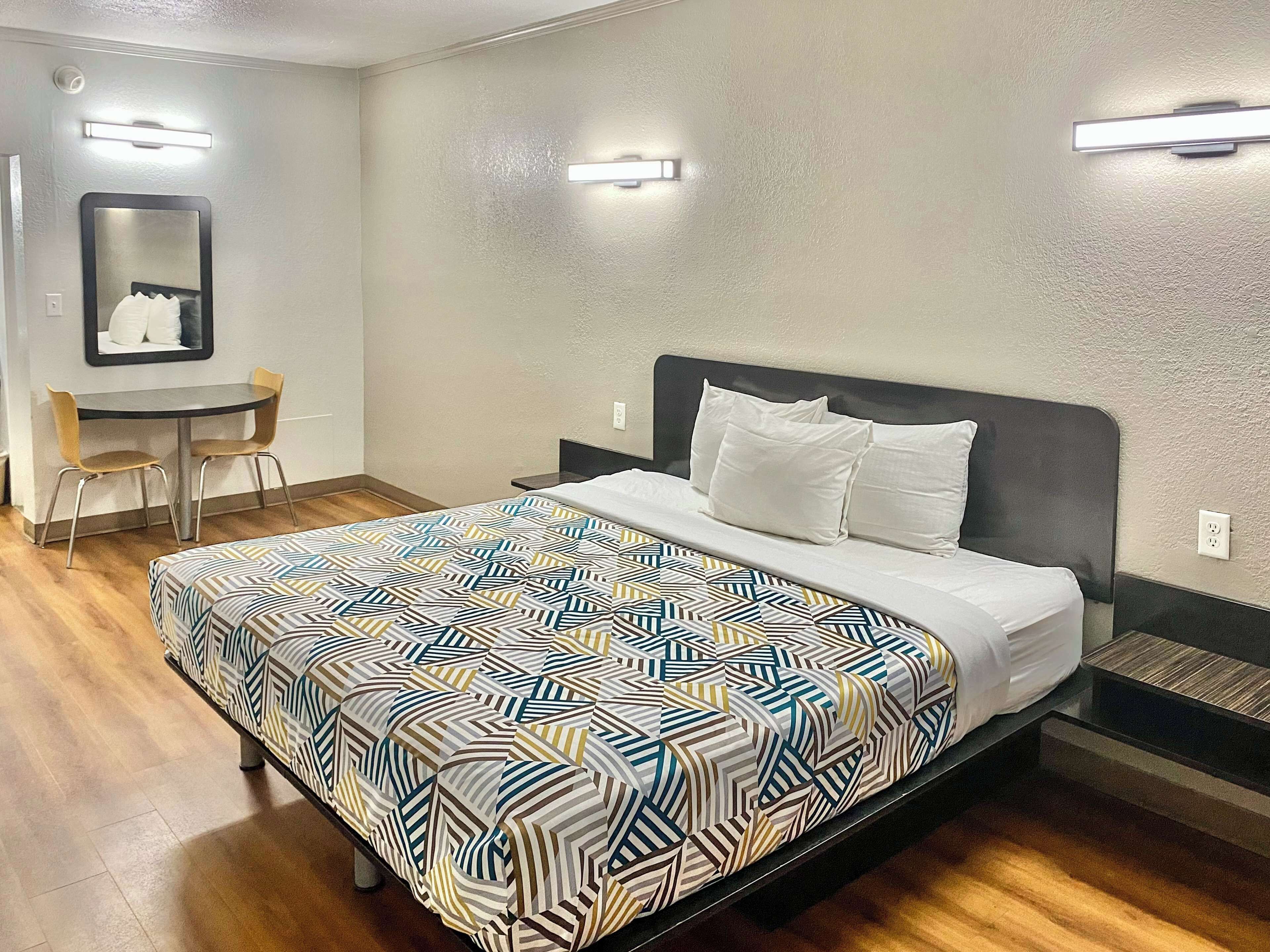 Une chambre d’hôtel avec un lit, un bureau et deux chaises.