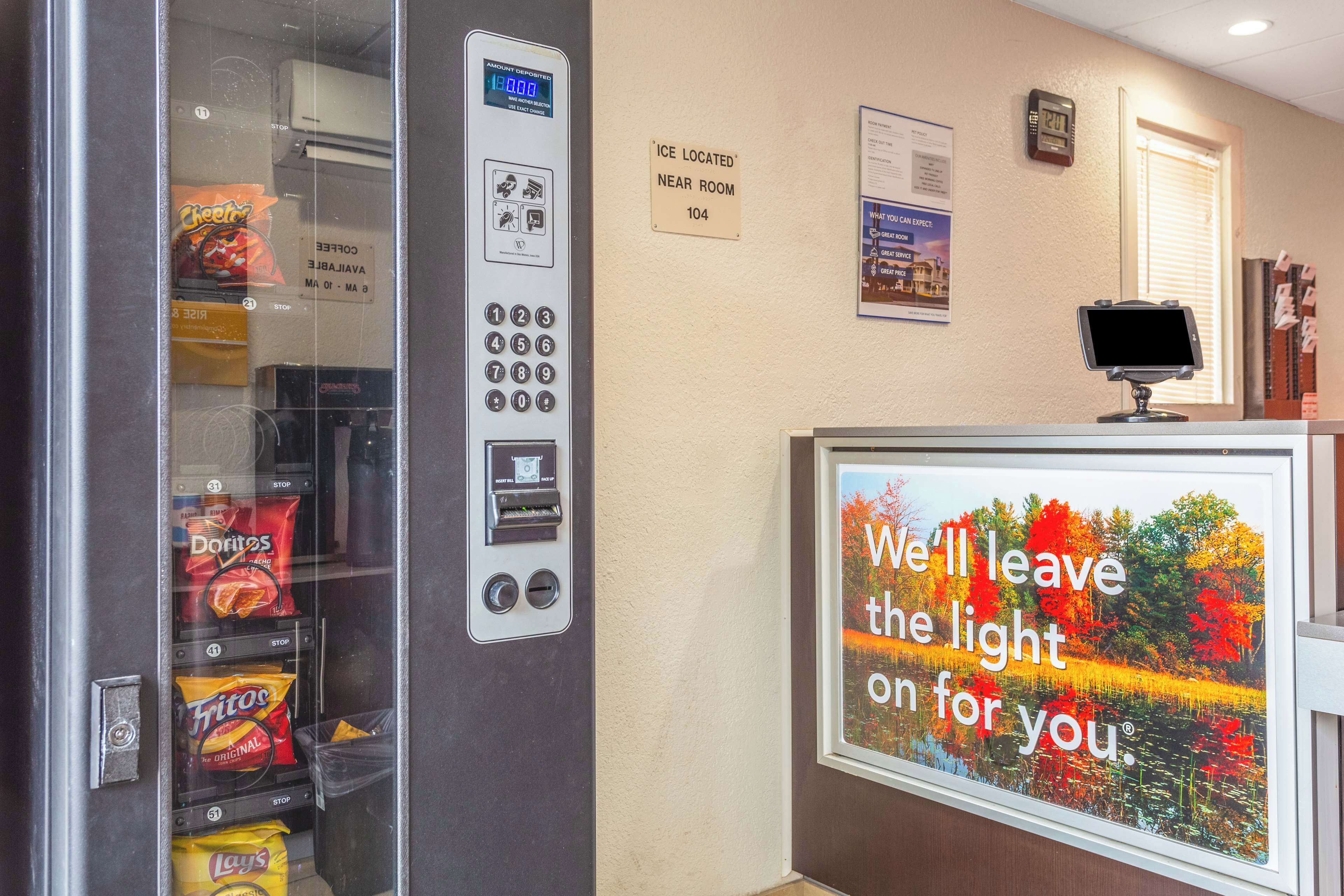 A vending machine with snacks, a digital clock, and a sign indicating an ice machine nearby.