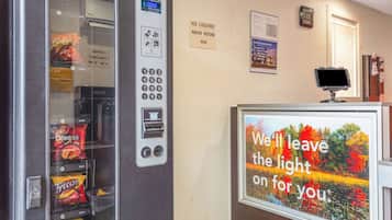 A vending machine with snacks, a digital clock, and a sign indicating an ice machine nearby.