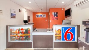 A motel lobby with a reception desk, a television, and a sign indicating the motel's name. - Motel 6 Huntington, WV (Huntington)