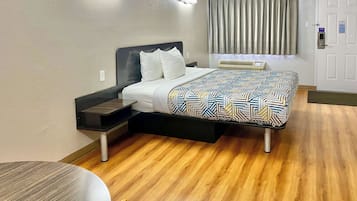 A hotel room with a bed, bedside table, and a small table with a chair.