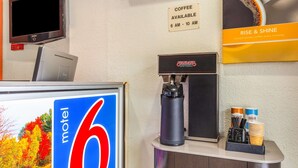 A coffee machine, a sign indicating coffee availability, and a 'Rise & Shine' coffee sign. - Motel 6 Huntington, WV (Huntington)
