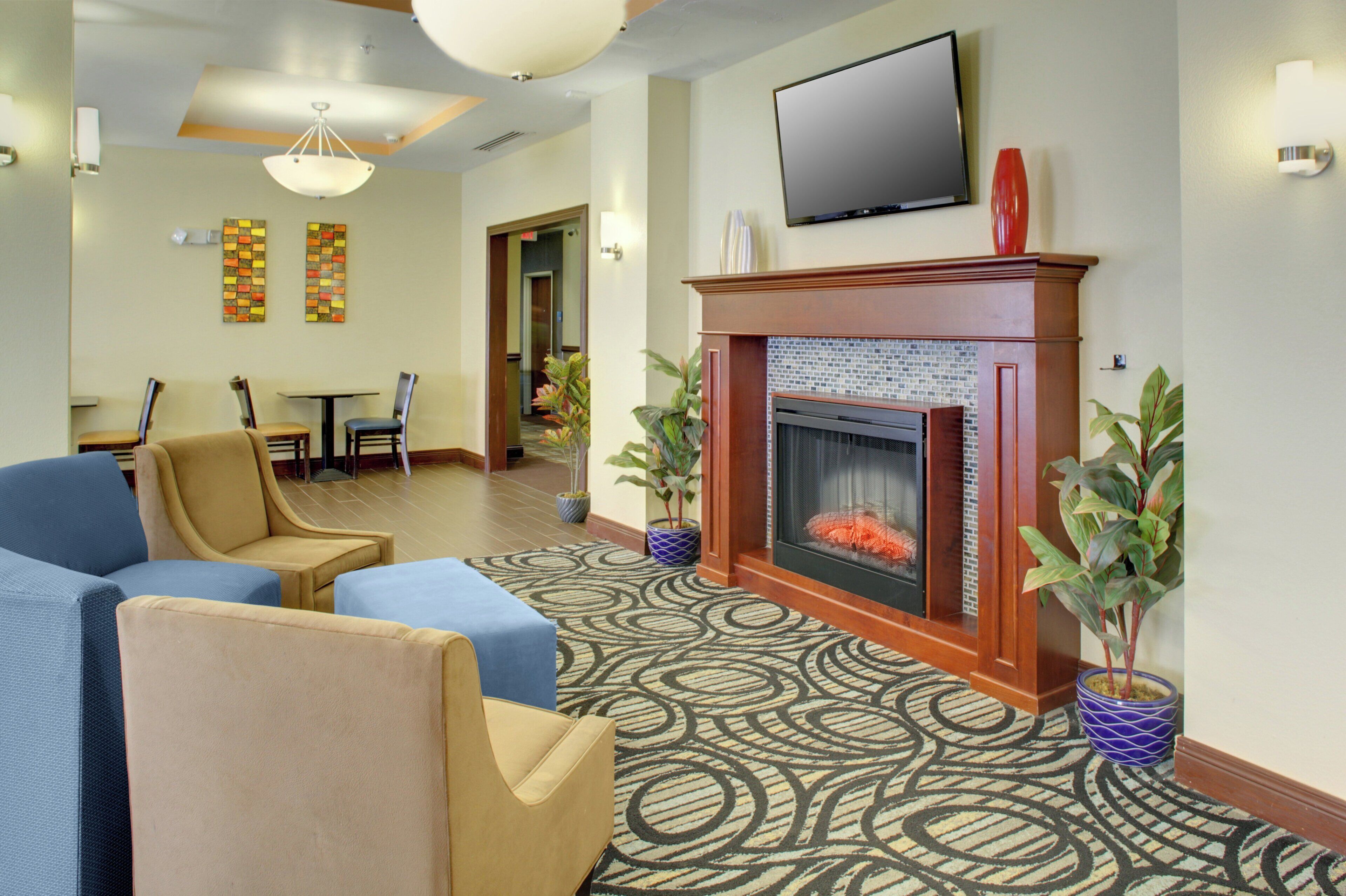 A hotel lobby with a fireplace, seating area, and a television mounted on the wall.