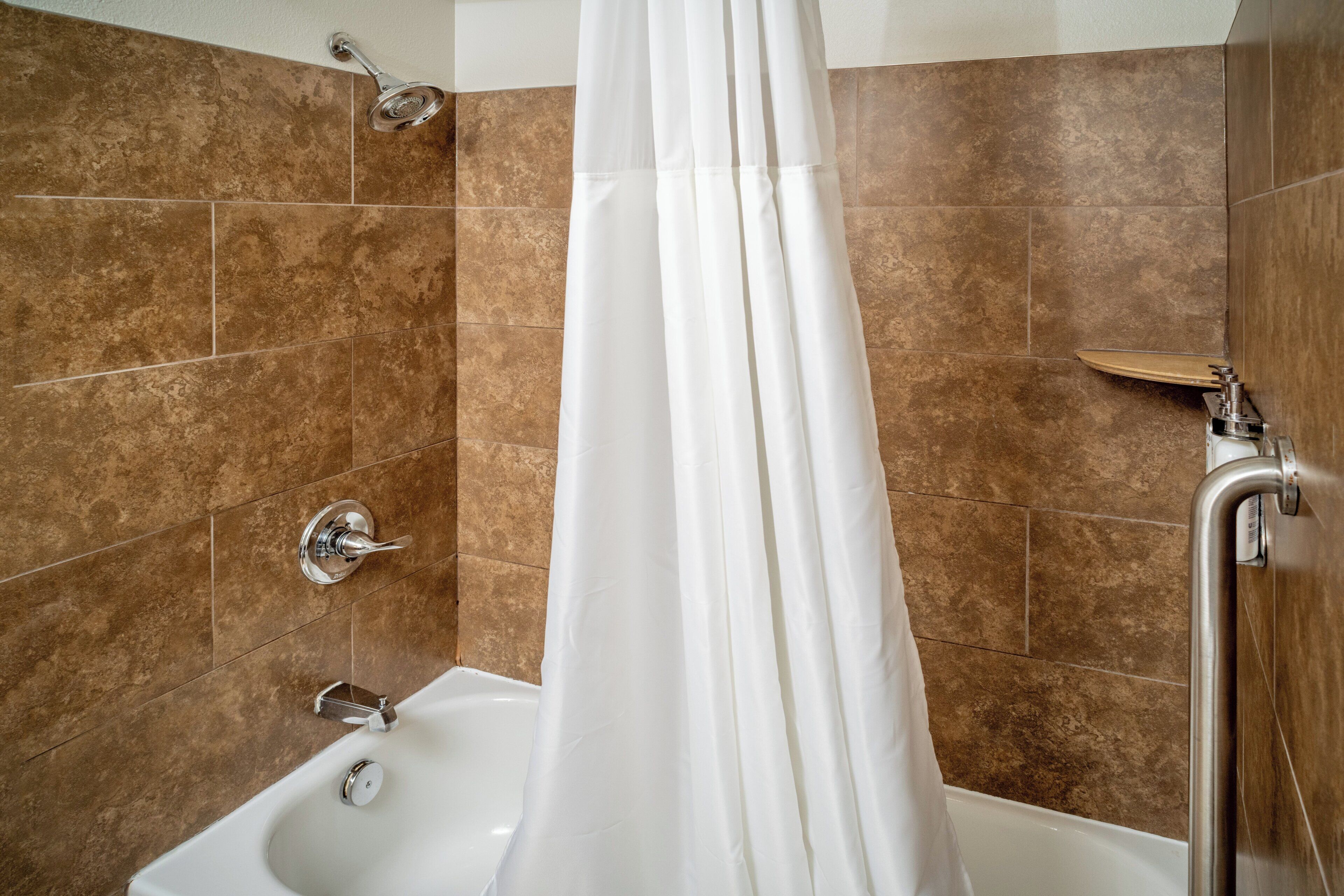 A modern bathroom with a bathtub, shower, and a curtain.