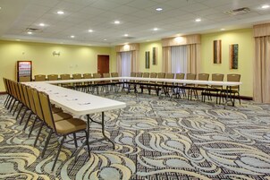 Un salón de conferencias con una larga mesa y sillas, suelo alfombrado y una puerta al fondo.