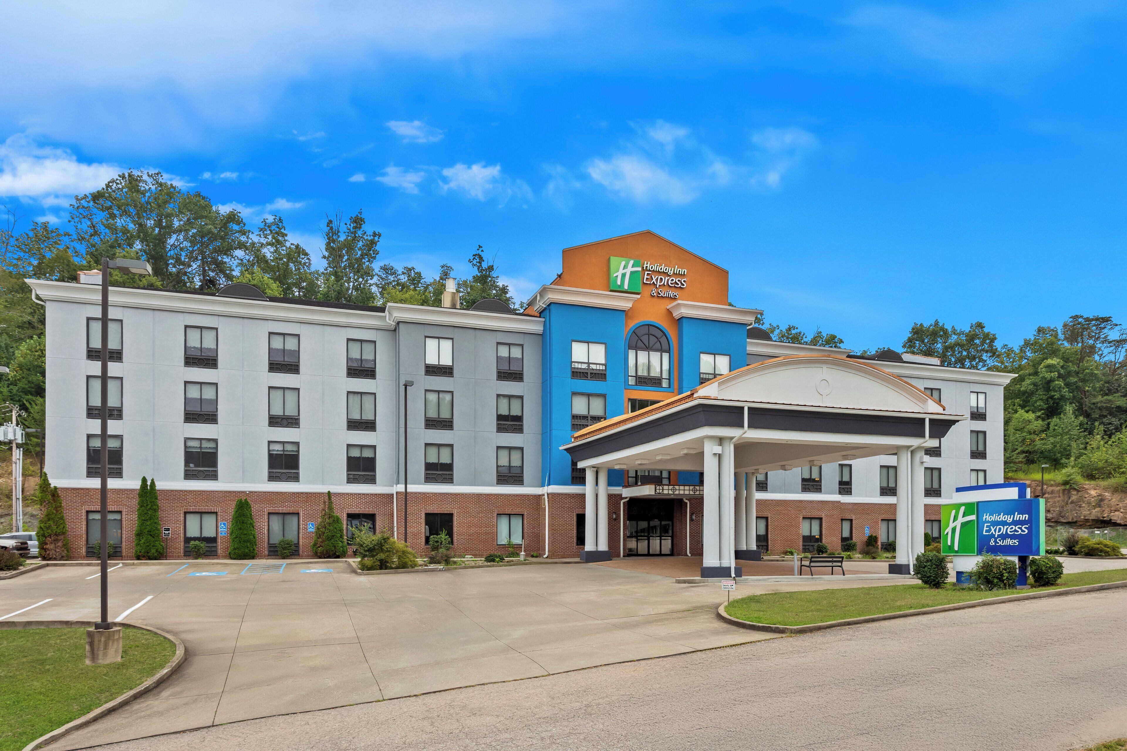 A Holiday Inn Express & Suites hotel with a modern design, featuring a prominent entrance and a parking lot.