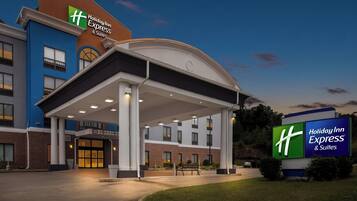 A Holiday Inn Express & Suites hotel entrance with a covered outdoor area and a parking lot.