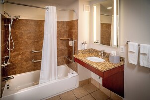 A modern bathroom with a bathtub, shower, vanity with a sink, and a mirror.