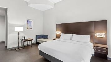 A modern hotel room with a large bed, bedside tables, a desk, and a chair.