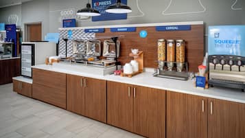 A breakfast bar with labeled dispensers for yogurt, eggs, milk, hot food, bakery, and cereal.