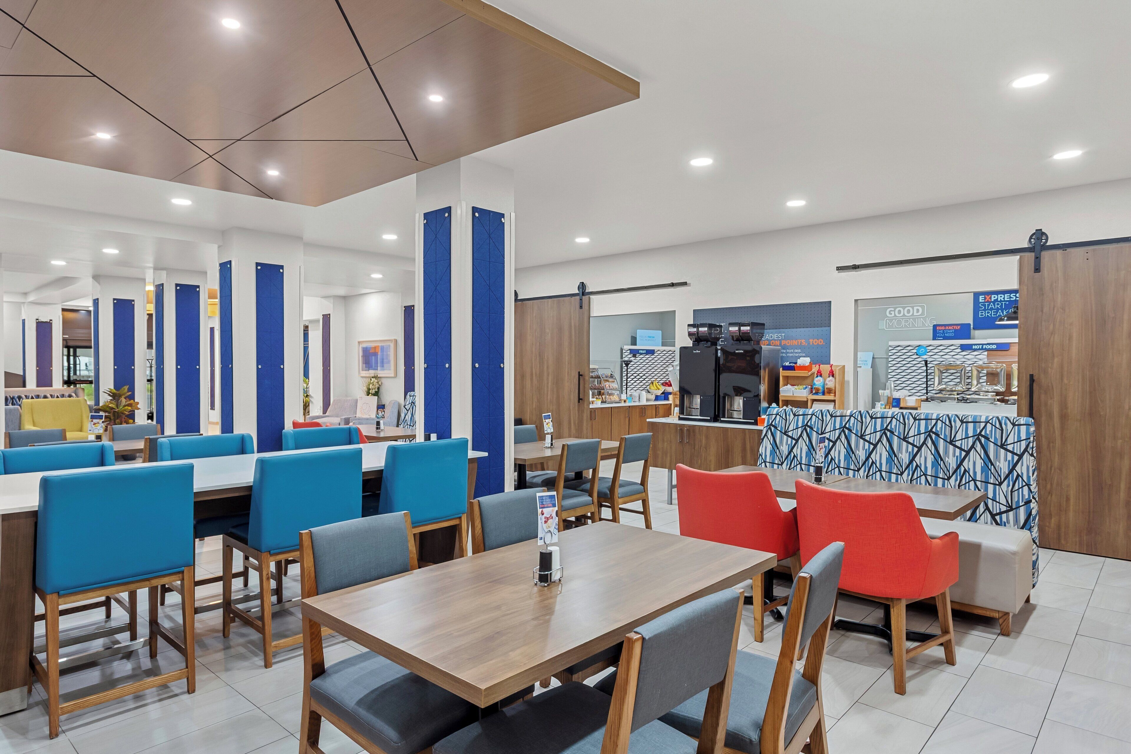 A modern dining area with booths and tables, a coffee station, and a breakfast bar.