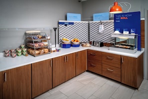 A breakfast station with a variety of food options, including fruits, pastries, and a coffee machine. - Holiday Inn Express Hotel & Suites Cross Lanes by IHG (Cross Lanes)