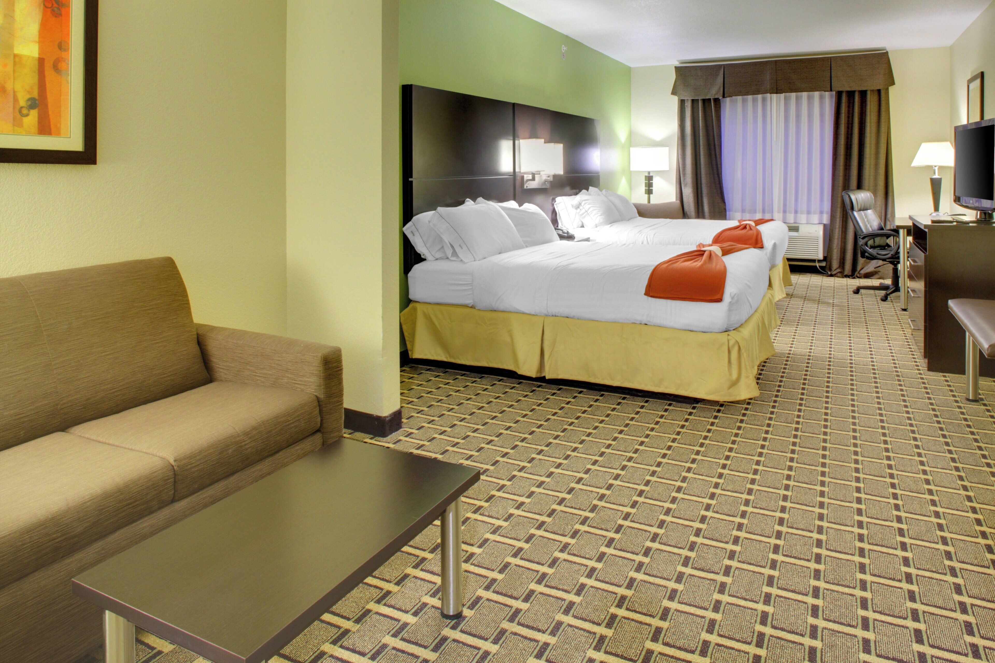 A hotel room with a bed, a sofa, a desk, and a television.