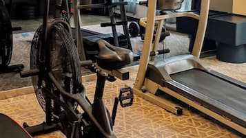 Ein stationäres Fahrrad, Laufband und Hanteln in einem Fitnessstudio.