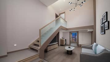 A modern interior with a staircase, a living area, and a view of the cityscape.