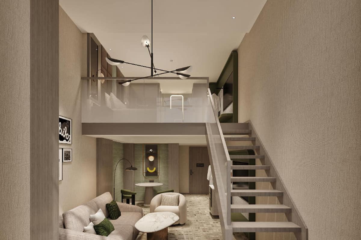 A modern interior with a staircase, a sofa set, a round table, and a wall-mounted light fixture.