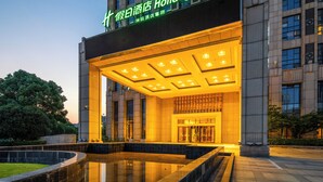 A hotel entrance with a large illuminated sign, a reflective pool, and a well-lit interior. - Holiday Inn Hefei City Center by IHG (Hefei)