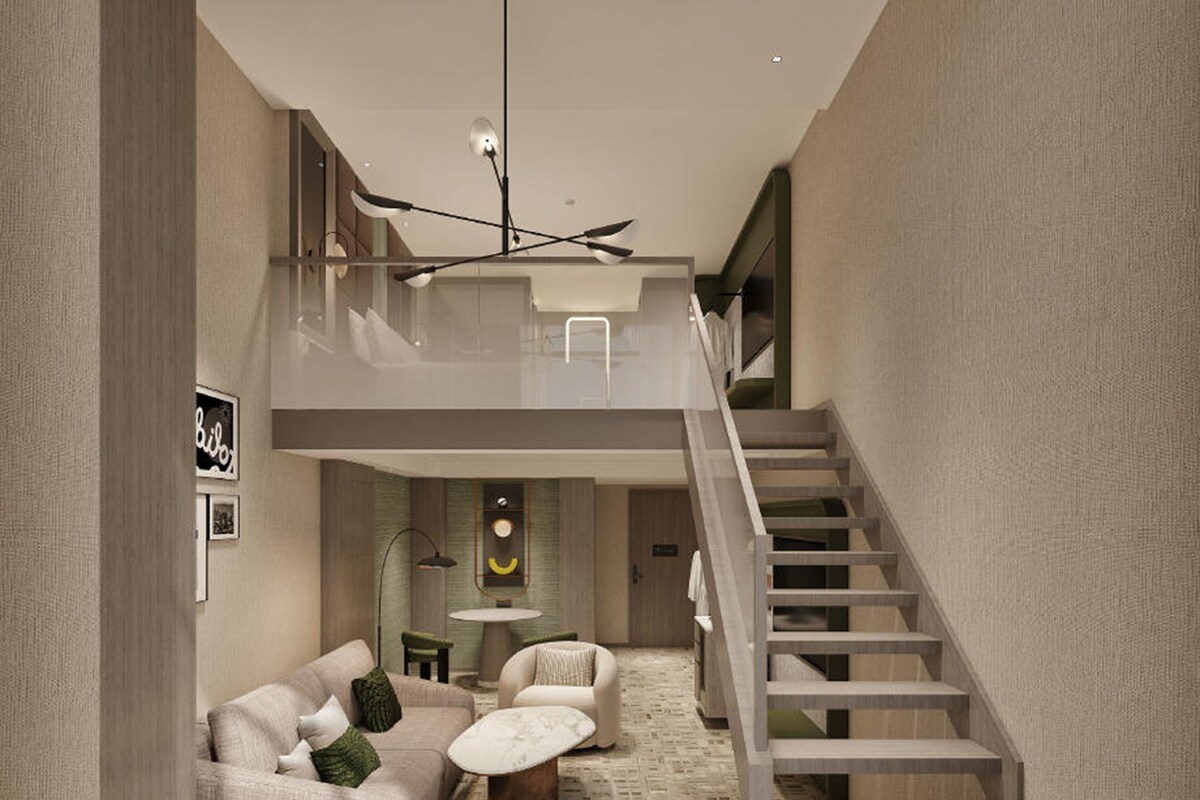 A modern interior with a staircase, a sofa set, a round table, and a wall-mounted light fixture.