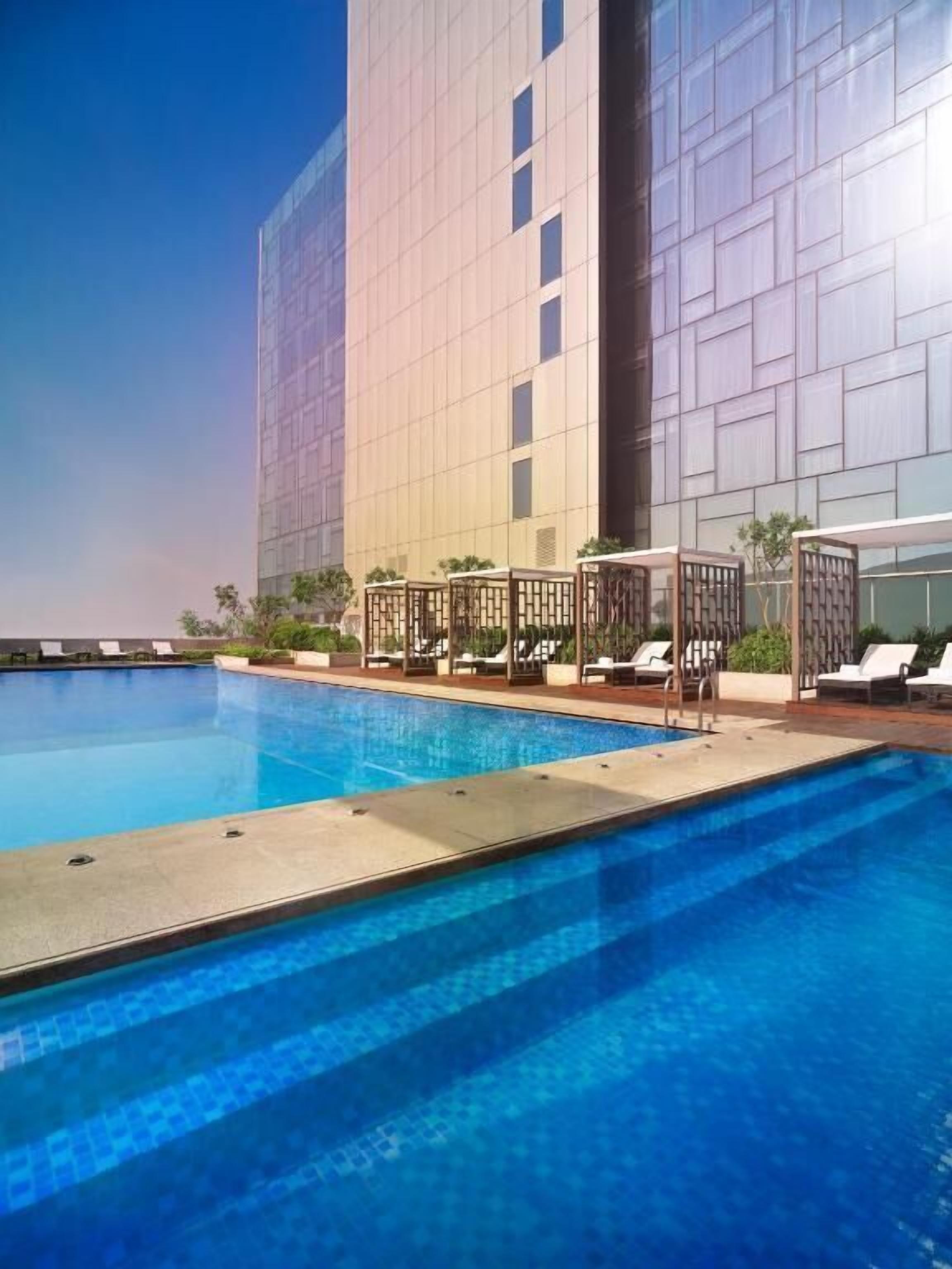 A swimming pool with lounge chairs and a modern building in the background.
