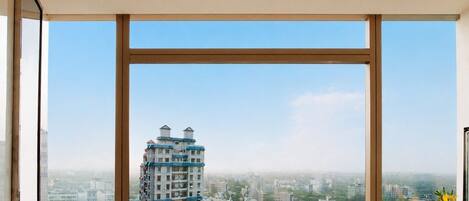 A high-rise building with multiple balconies, a clear sky, and a view of a residential area.
