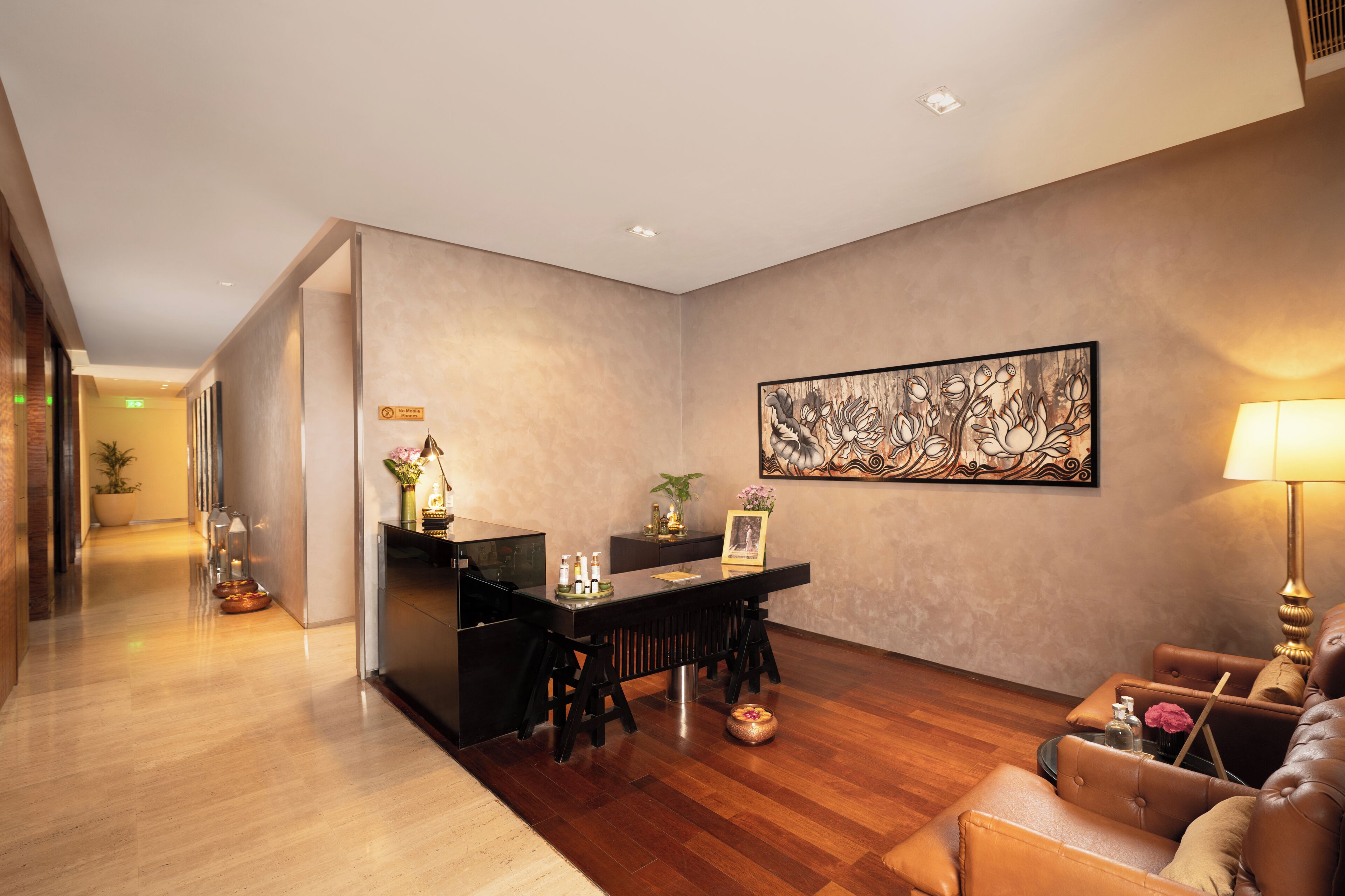 A hotel lobby with a reception desk, seating area, and a large abstract painting on the wall.
