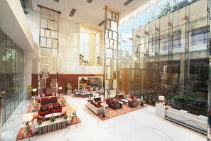 A spacious lobby with a high ceiling, marble flooring, and a seating area with sofas and tables. - Taj City Centre Gurugram (Gurugram)