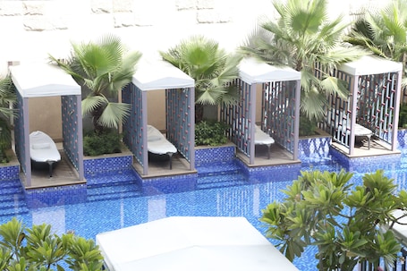 Una piscina al aire libre, sombrillas, sillones reclinables de piscina