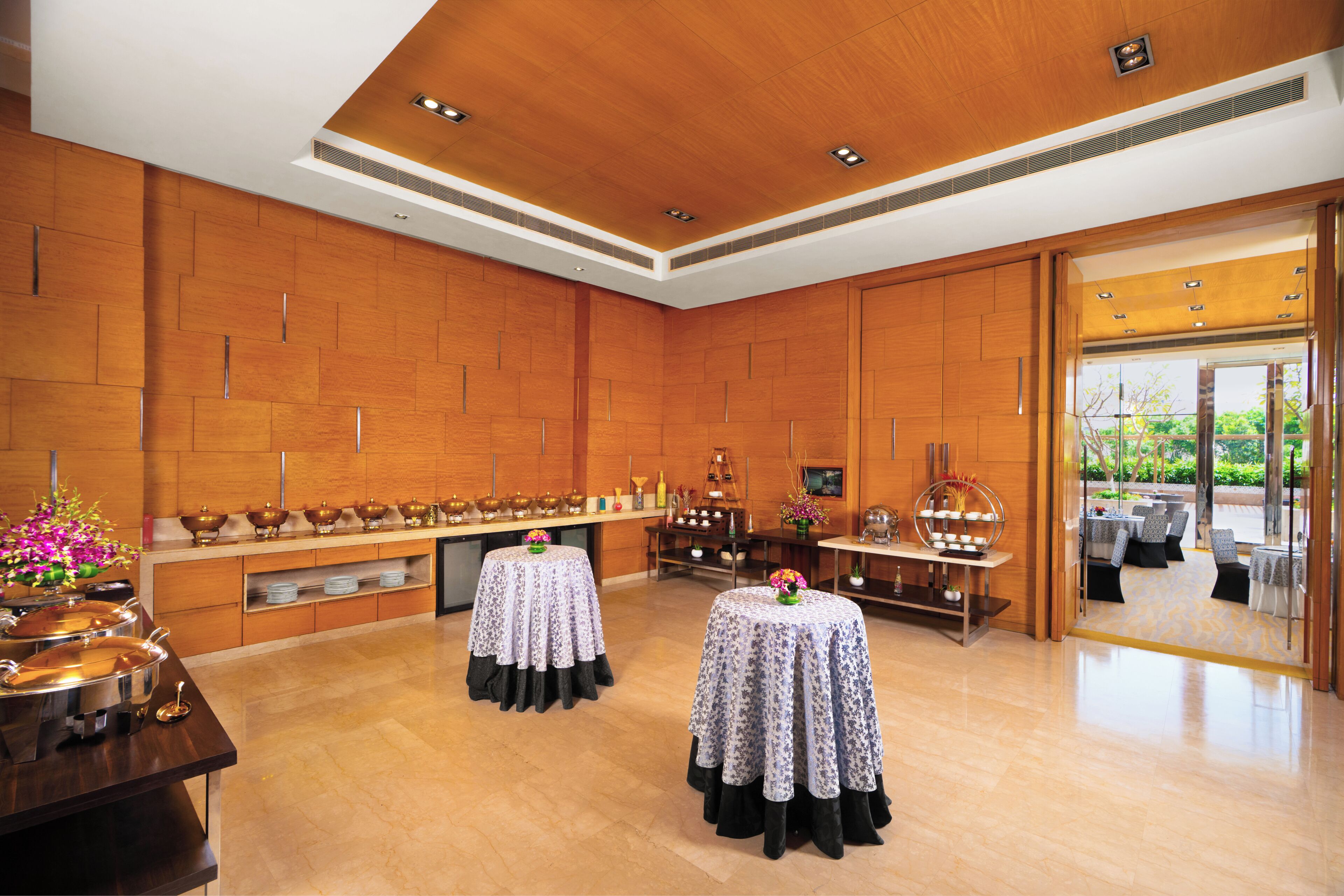 Amplia habitación con paneles de madera, una disposición tipo buffet y vistas a través de un ventanal.