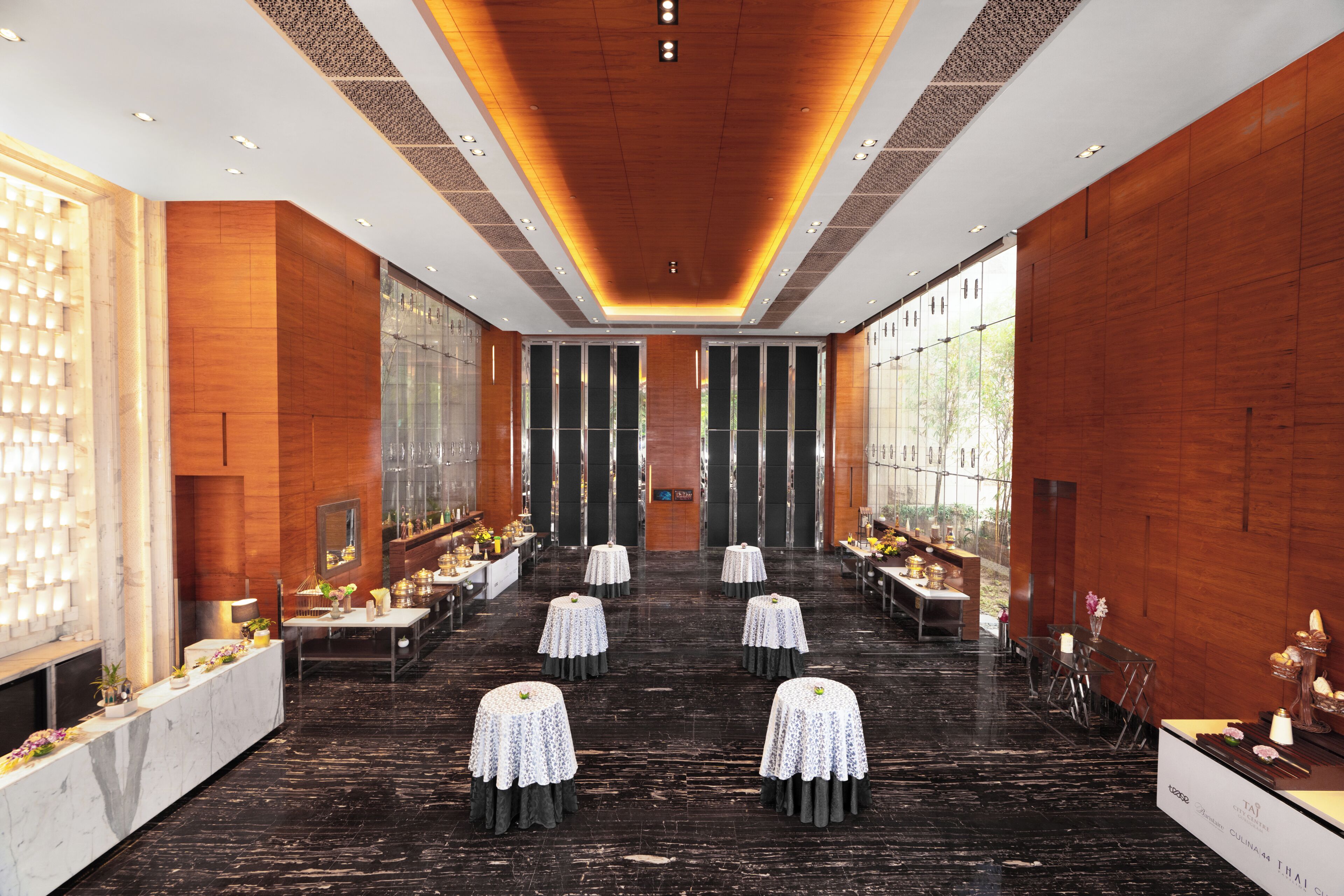 Un hall d’hôtel spacieux, doté d’un espace salon central, de grandes fenêtres et d’un design moderne.