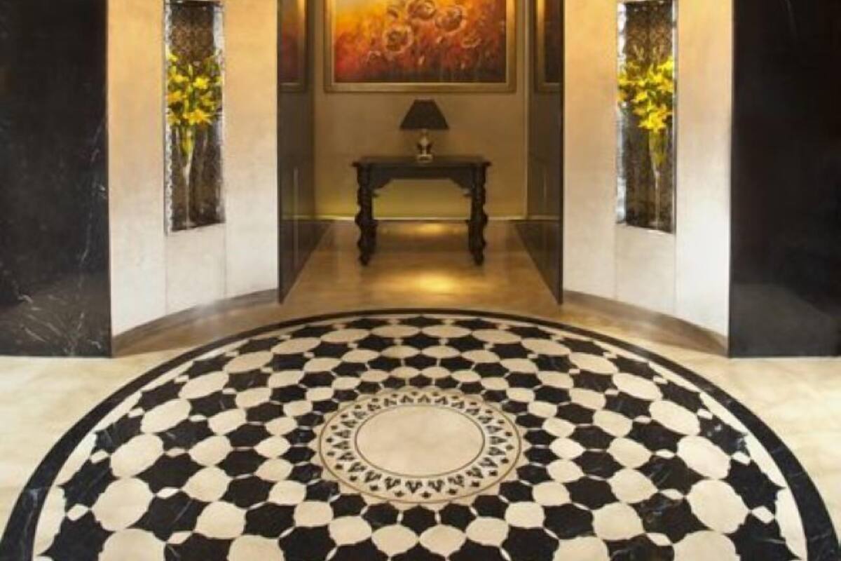 A lobby with a circular patterned floor, a chandelier, and artwork on the walls.