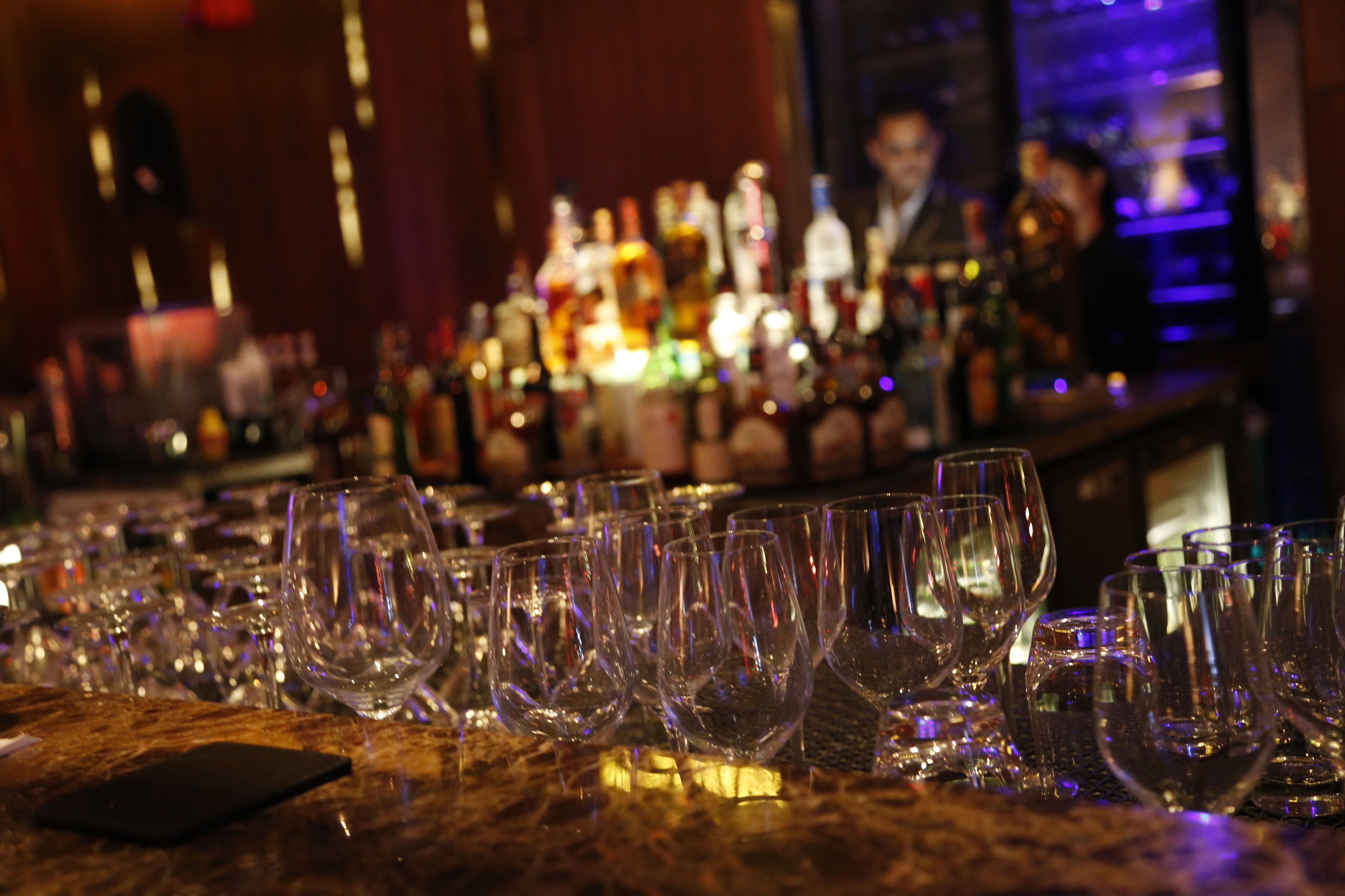 Un bar où l’on voit de nombreux verres à vin vides et des bouteilles à l’arrière-plan.