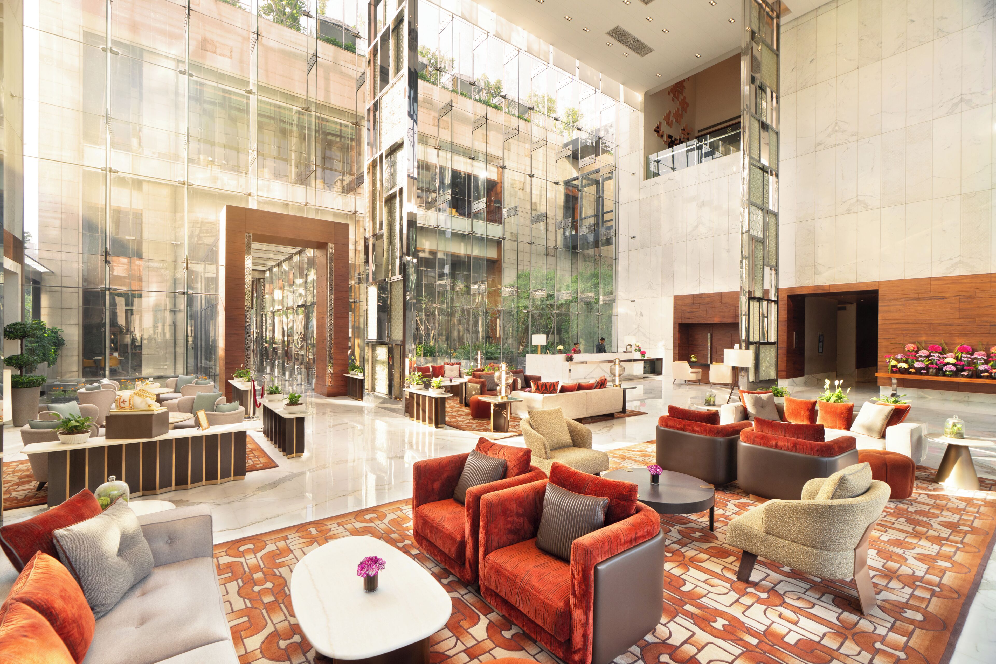 A spacious lobby with multiple seating areas, a reception desk, and a large glass wall offering views of the outdoors.