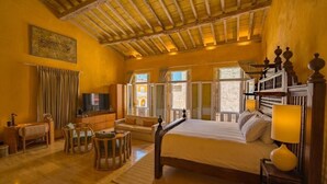 Ein Schlafzimmer mit Bett, Fernseher, Sofa und Essecke.