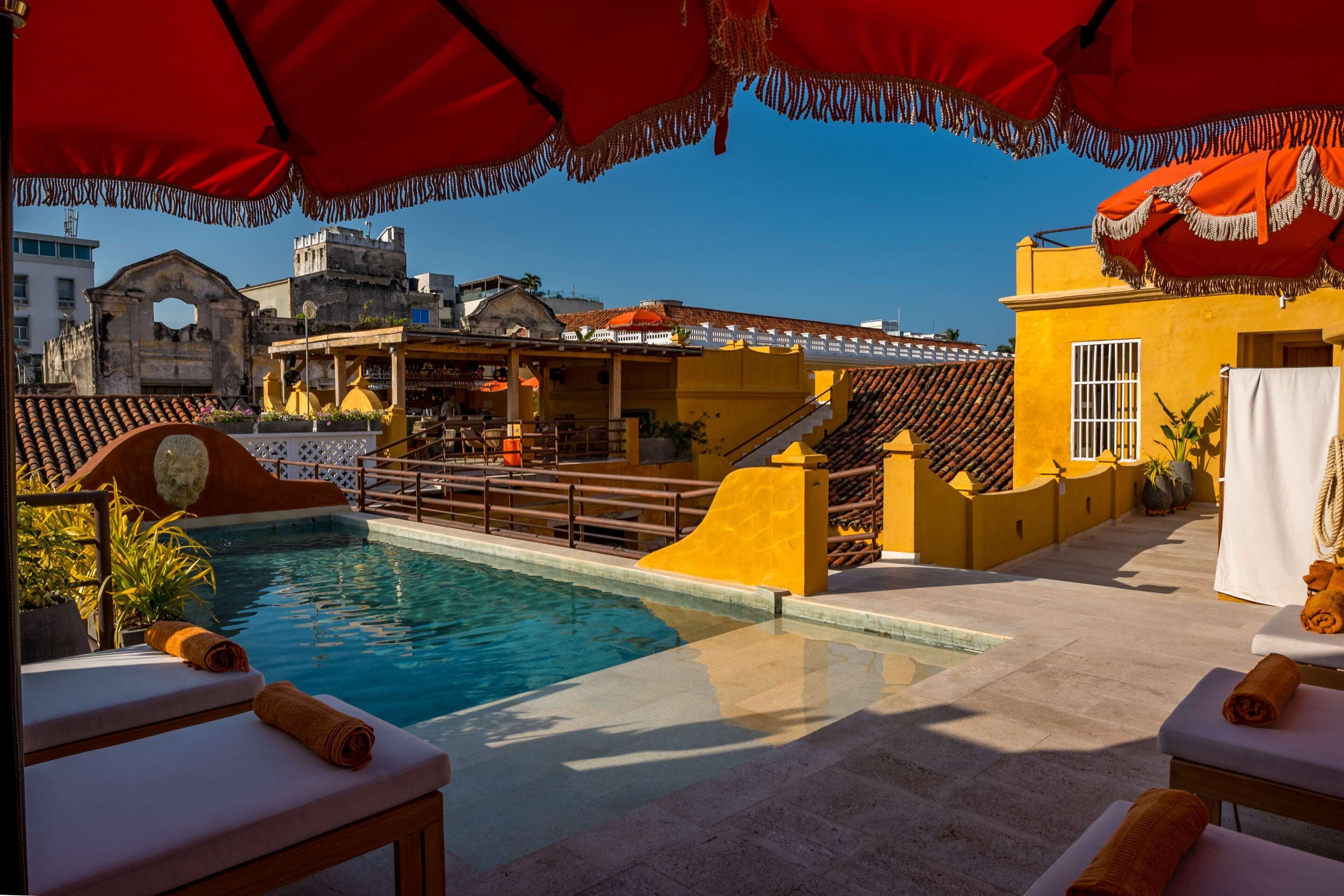 A pool area with lounge chairs, a staircase, and a view of historic buildings.