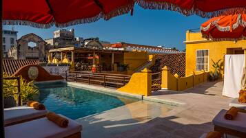 A pool area with lounge chairs, a staircase, and a view of historic buildings.