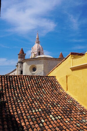 A building with a tiled roof and a church steeple in the background. - Casa Carolina Luxury Wellness Hotel (Cartagena)