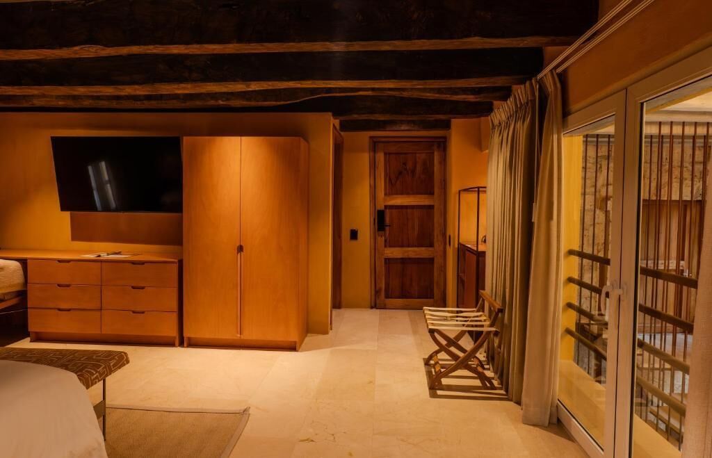 Una habitación con un armario de madera, televisor, cama, escritorio y una silla.