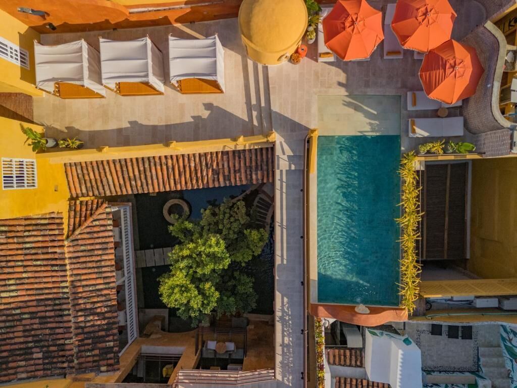 An aerial view of a hotel with a swimming pool, outdoor seating, and umbrellas.