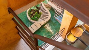Una escalera de caracol con un macetero central, una pequeña mesa con una silla y una barandilla.